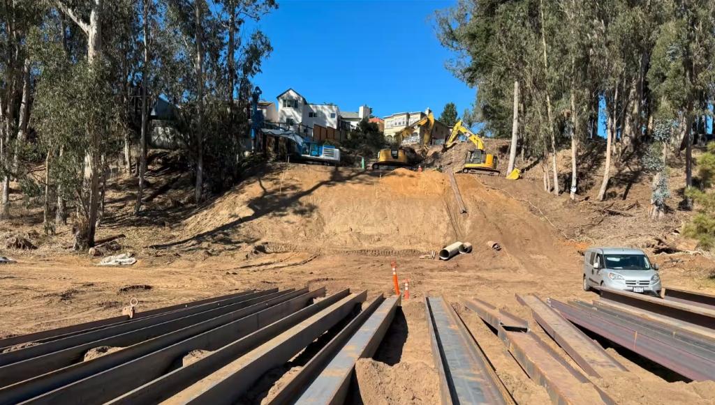 Image of restoration work on the slope, showing large machinery in the background and construction materials in the foreground