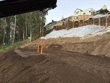 image of slope showing new soil laid down as well as the retaining wall