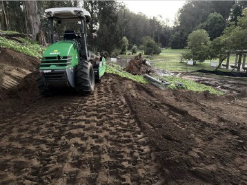 Image of tractor compacting soil on a flattened portion of the new slope