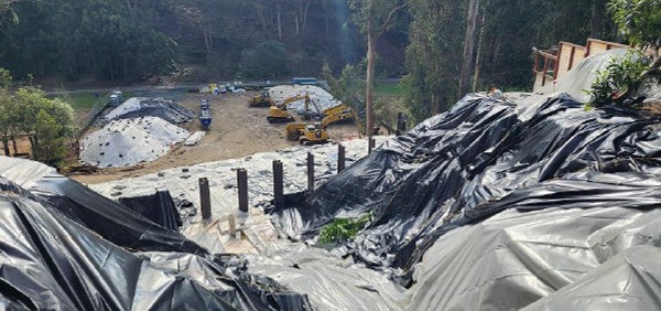 Photo shows plastic sheeting laid down on slope to prevent erosion