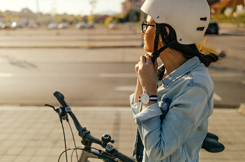 A girl holds her helmet next to an electric bike.