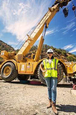 Intern wearing hard hat in front of tractor