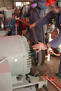 man pulling a belt onto a machine wheel