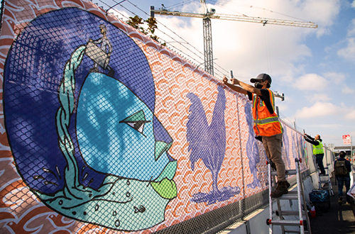 workers on ladders attending to the mural