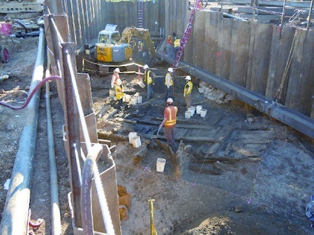 workers in a trench revealing the buried ship