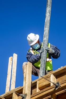 laborer guiding concrete pouring hose