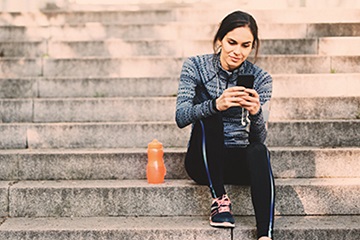 woman sitting on steps and texting on her phone