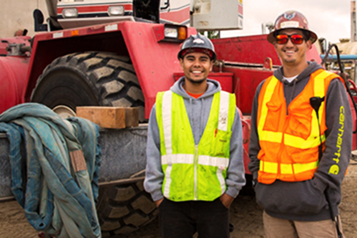 Dos trabajadores con derechos adquiridos de pie hombro con hombro delante de un tractor