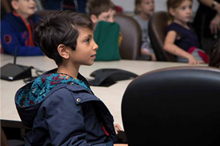 child facing a speaker in the classroom