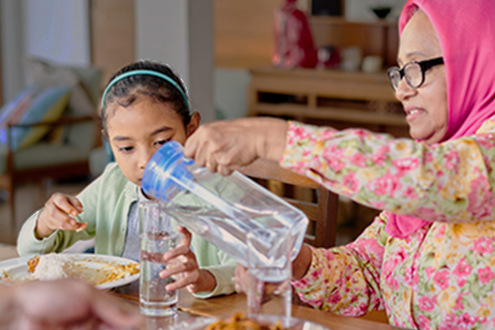 woman pouring water for a child from a pitcher