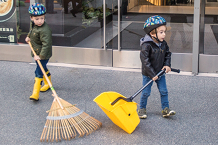 children sweeping leaves off the sidewalk