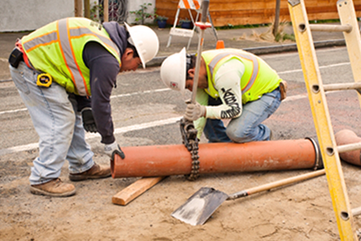 worker cutting a sewer pipe