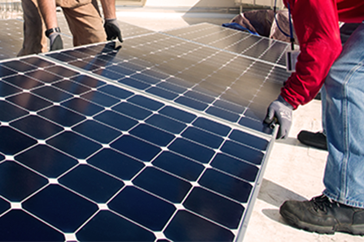 manos levantando un panel solar