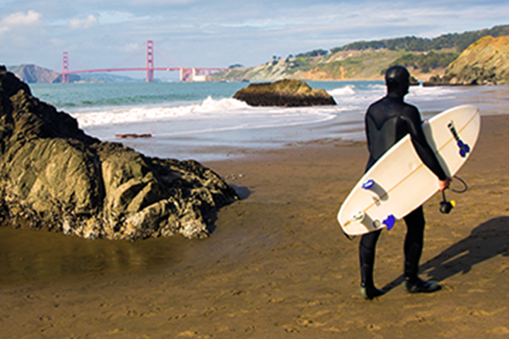 Surfista con tabla caminando en la playa de Baker