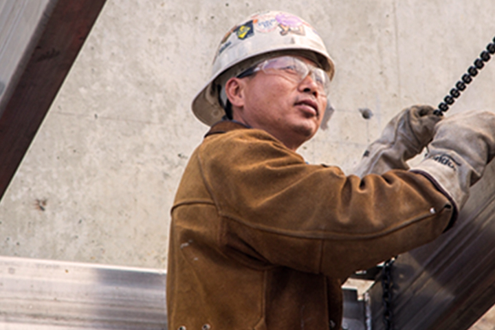 male construction worker in hard hat, protective goggles, gloves and leather coat