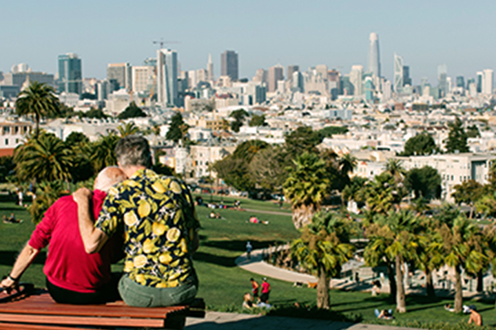 dalawang lalaki na nakaupo sa bench na tinatanaw ang Dolores Park