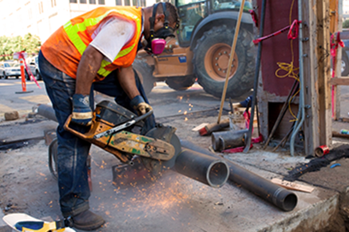 worker sawing a cast iron pipe