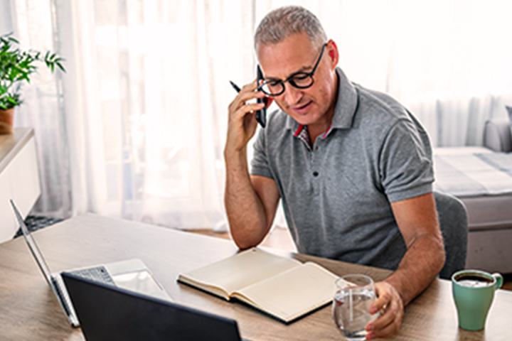 hombre en su escritorio y haciendo una llamada telefónica