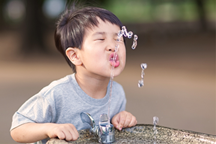 batang lalaki na umiinom mula sa water fountain