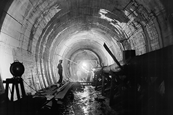 Historical photo of construction workers in large pipe