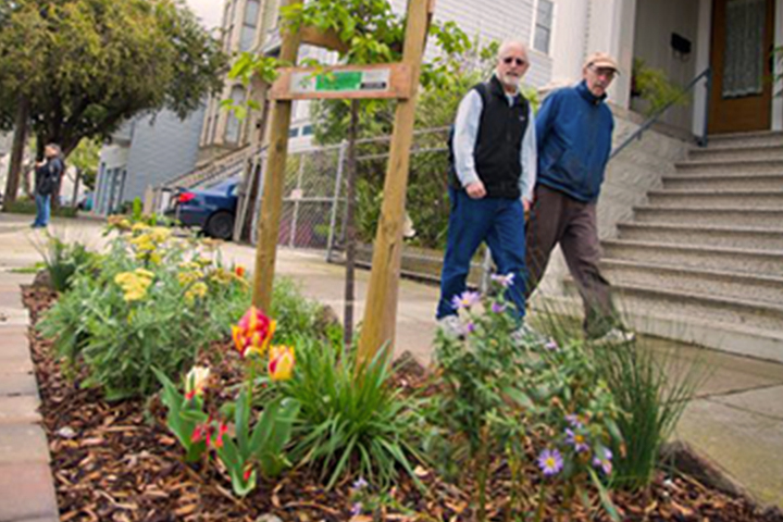 couple walking past sidewalk planter