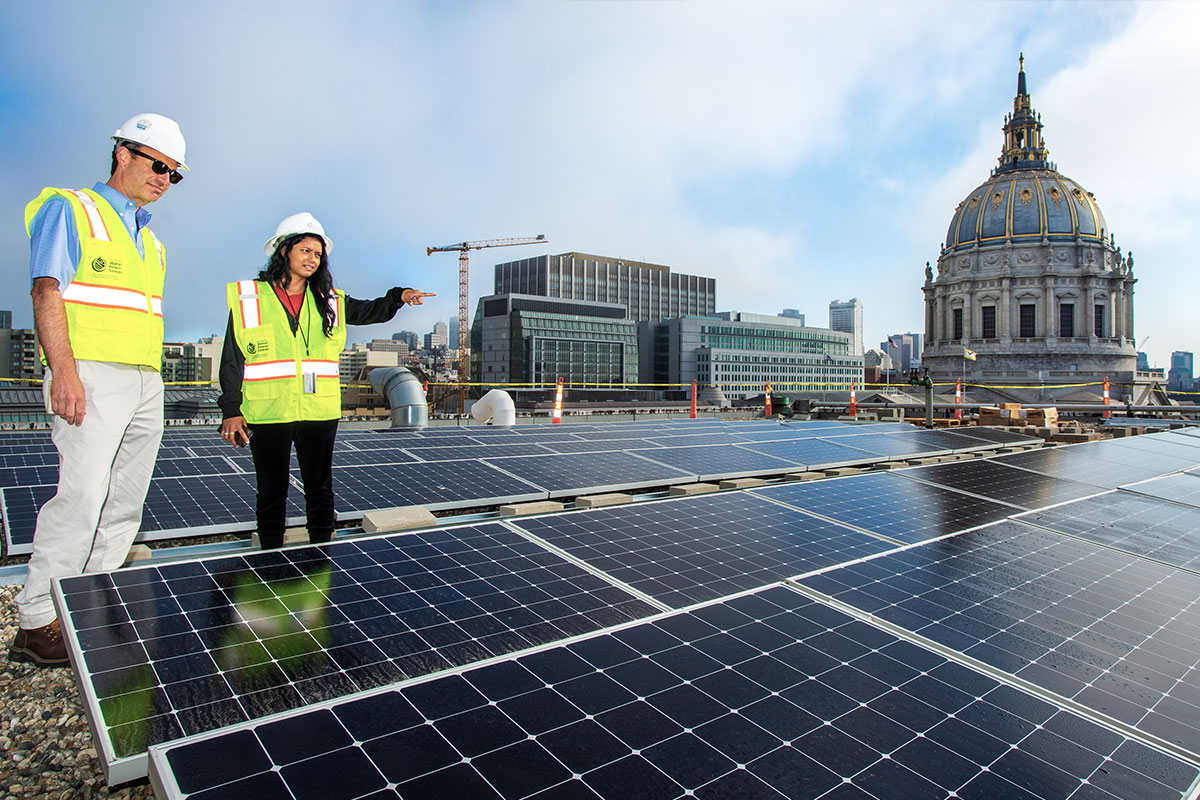 Dos empleados de la SFPUC miran los paneles solares en el Ayuntamiento.