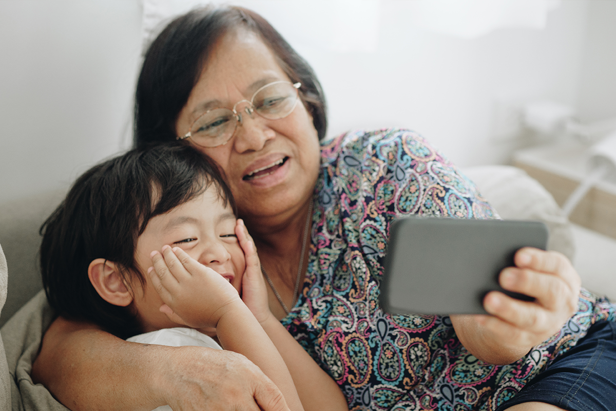 Una abuela y un nieto miran juntos un teléfono.