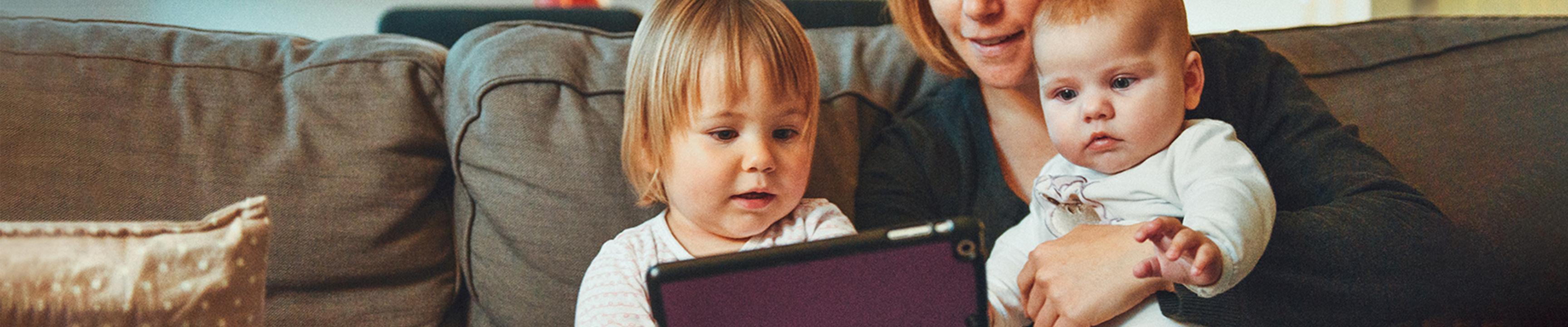 Mujeres y niños en el sofá mirando una computadora portátil