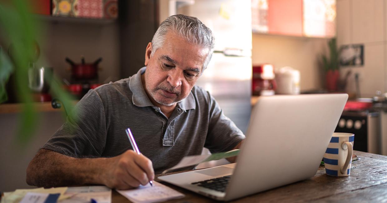 Person sitting at table looking at a bill and writing a check.