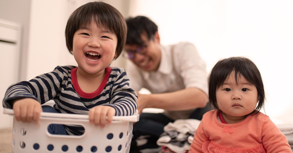 Two children with parent doing laundry.