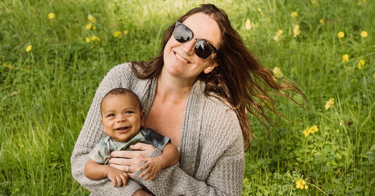 SFPUC Pollution Prevention Specialist Autumn Ross holding her baby in a grassy field