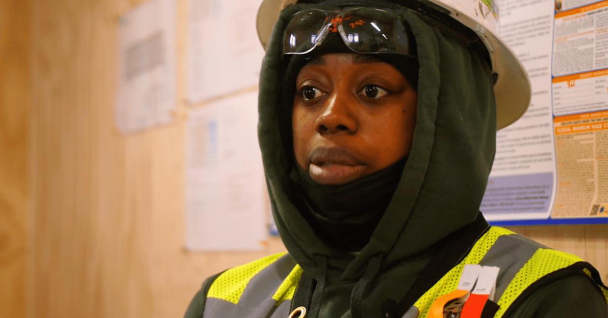 Shabrea Thornton wearing a construction vest and hardhat over her sweatshirt hood