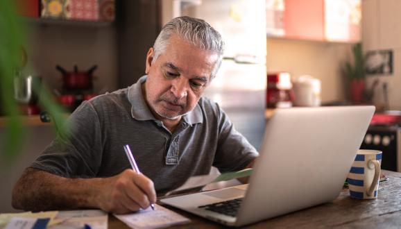 Person sitting at table looking at a bill and writing a check.