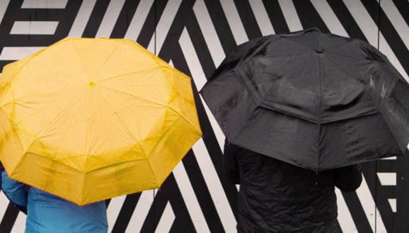 Two umbrellas against a striped wall.