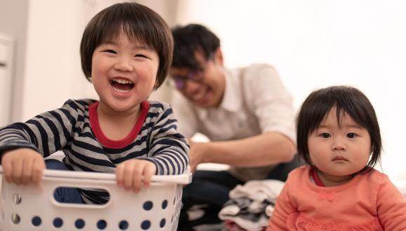 Two children with parent doing laundry.