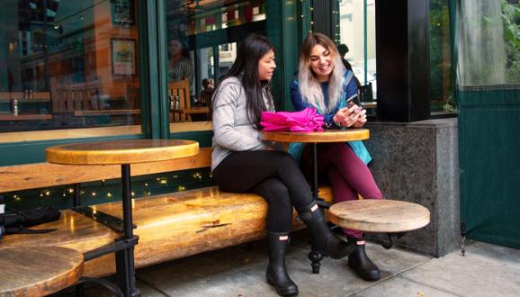 Two people sit outside a business talking.