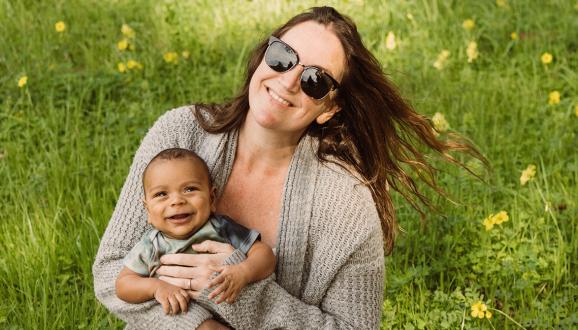 SFPUC Pollution Prevention Specialist Autumn Ross holding her baby in a grassy field