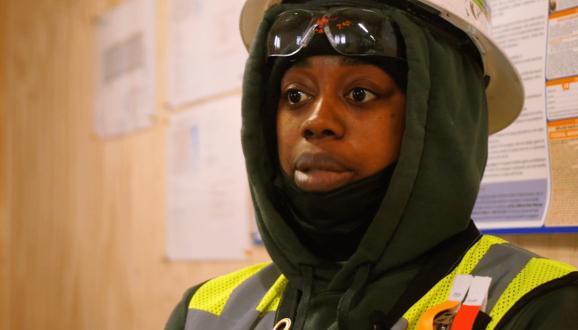 Shabrea Thornton wearing a construction vest and hardhat over her sweatshirt hood