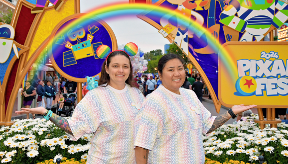 Milyn and her wife, celebrating Pride at Pixar Fest in front of a rainbow